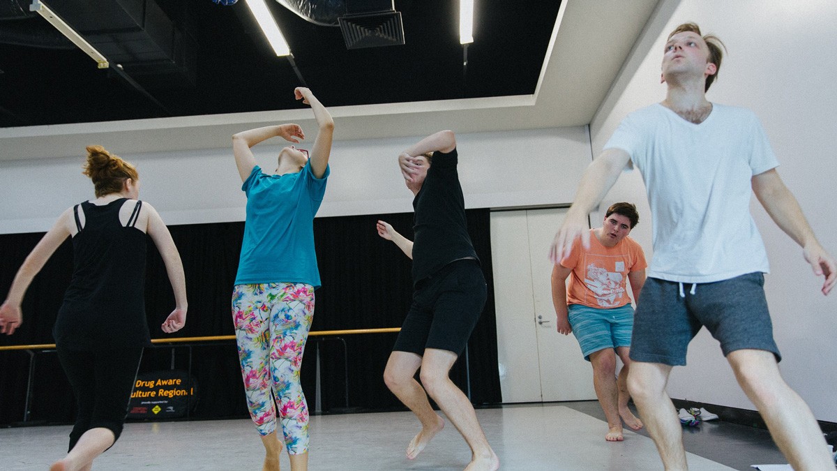 Five individuals dancing around each other in casual clothing.