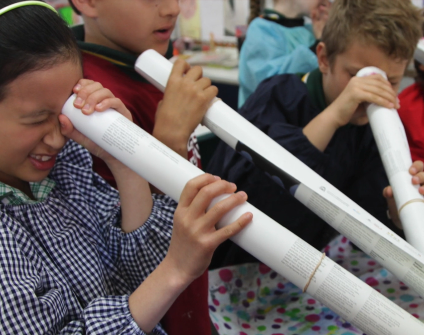 Group of children holding rolled-up paper like telescopes