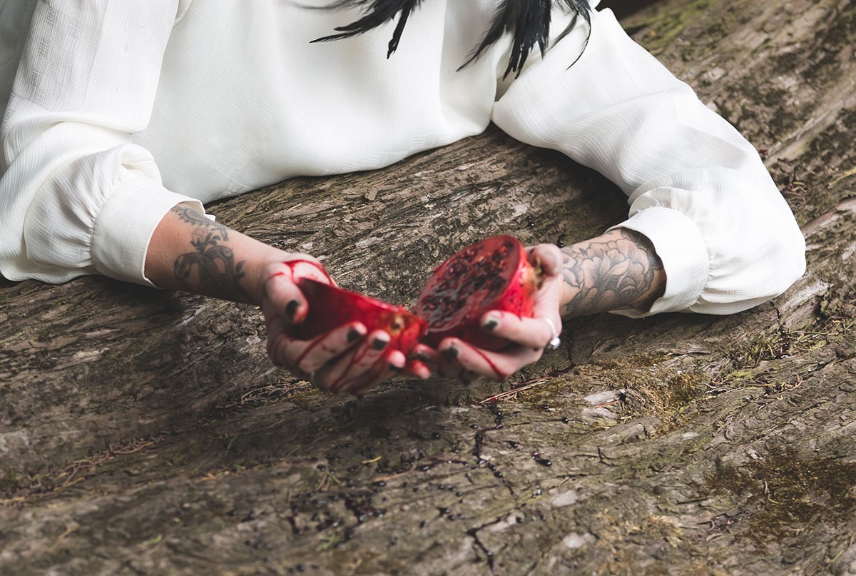 Close up of hands holding a cut in half pomegranate.