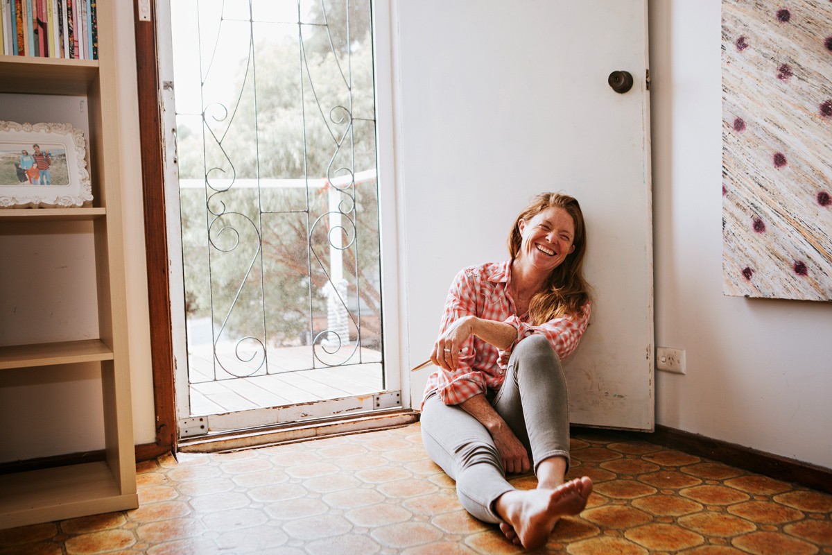 Person sitting on the floor laughing with the door open.