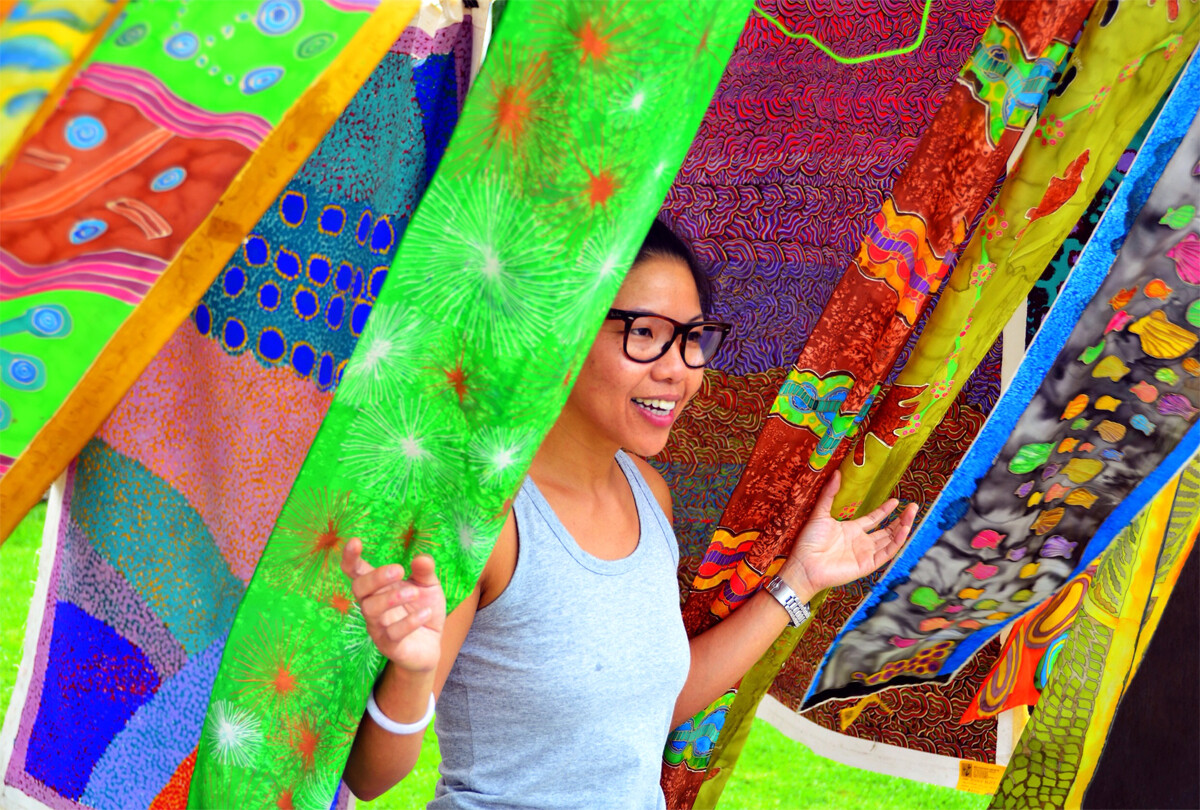 Person emerging from rainbow coloured fabrics.