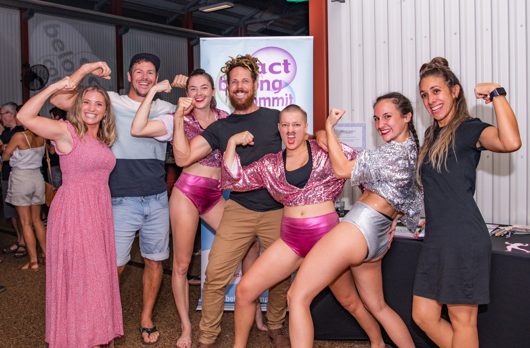 Groupof people holding strong poses, dressed in pink and grey outfits.