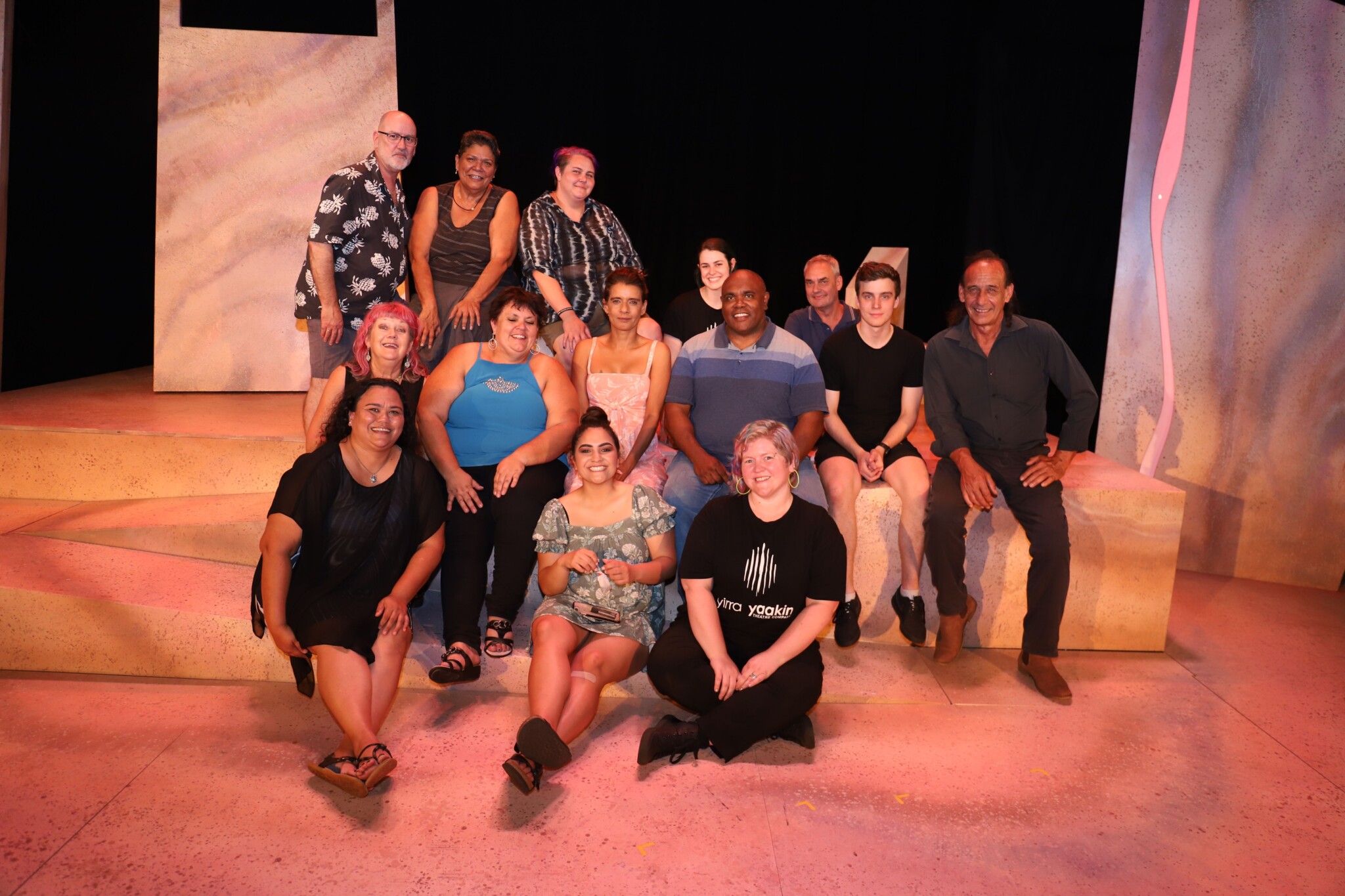 Cast and creative sit and stand on stage as a group