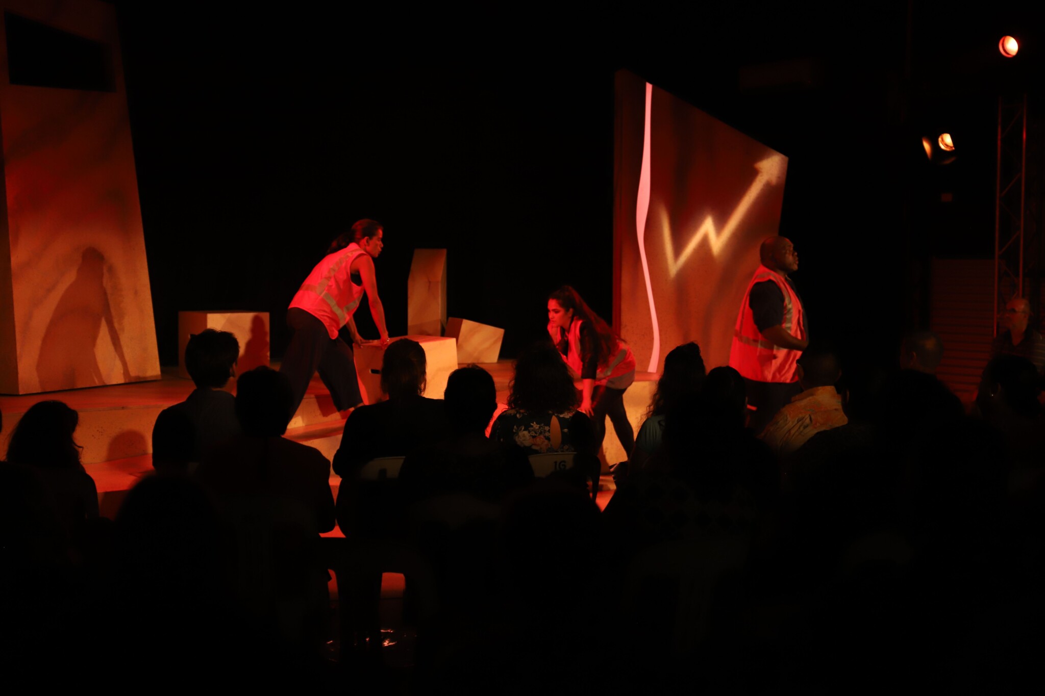 Load, Dump, Drive scene being performed on stage by cast in hi-vis vests 