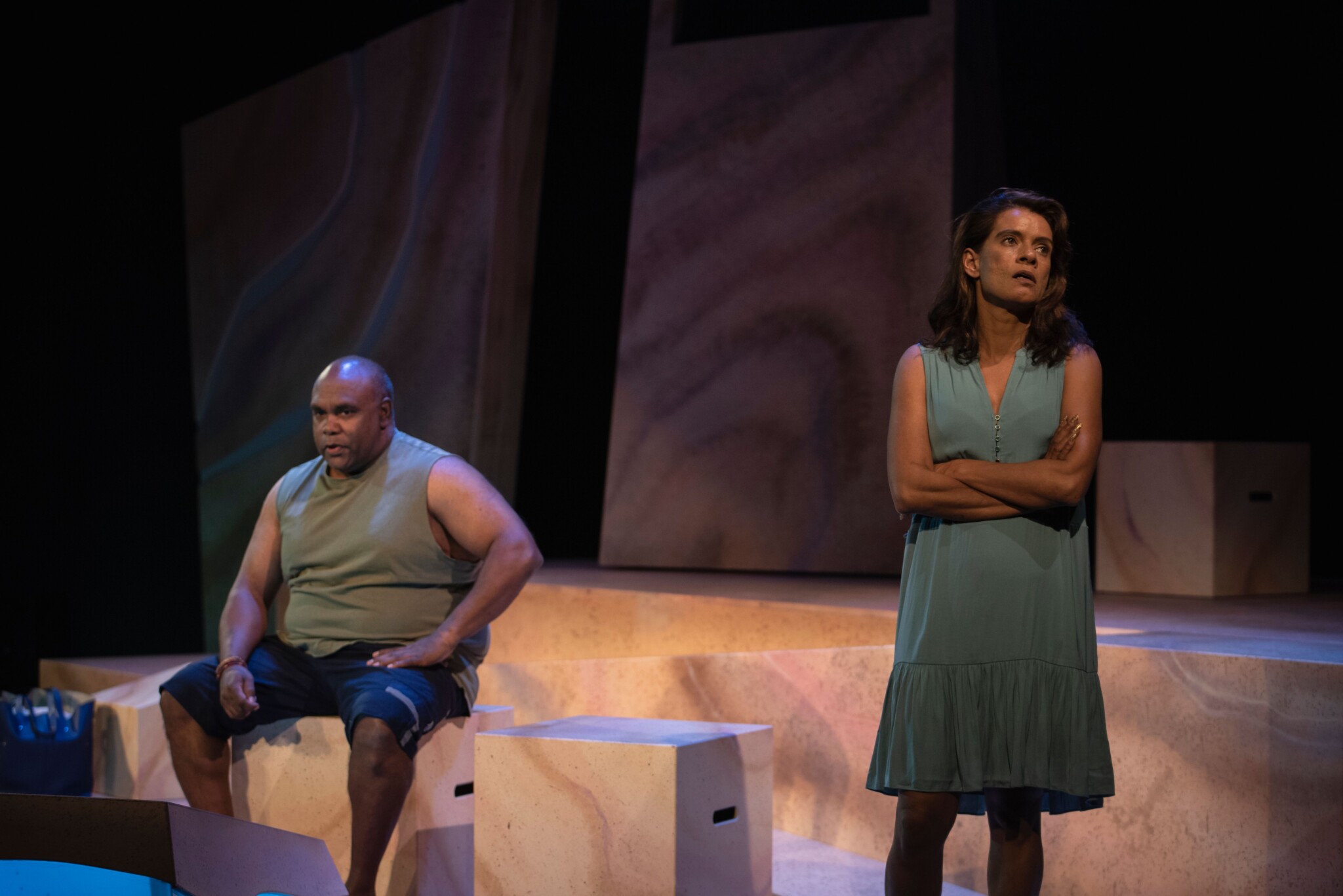 Trevor Ryan sits on the stage, Bobbi Henry has her arms crossed and back to him as if angry