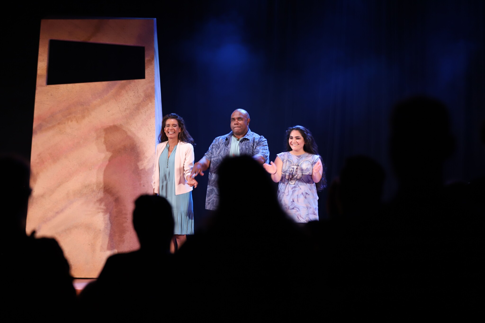 the cast claps on stage as the audience gives a standing ovation