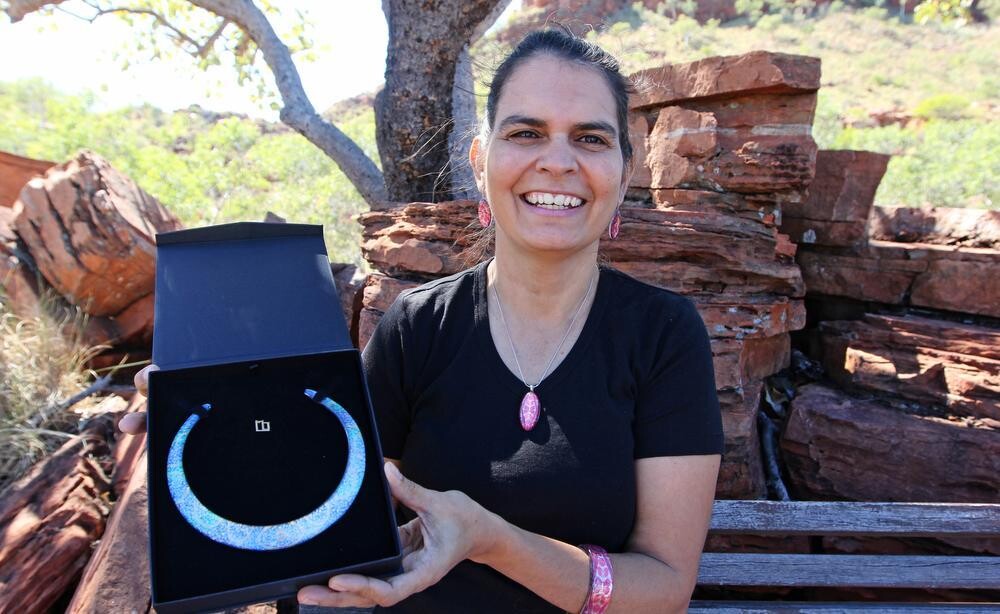 Person holds up box containing a necklace, shot outside in the bush.