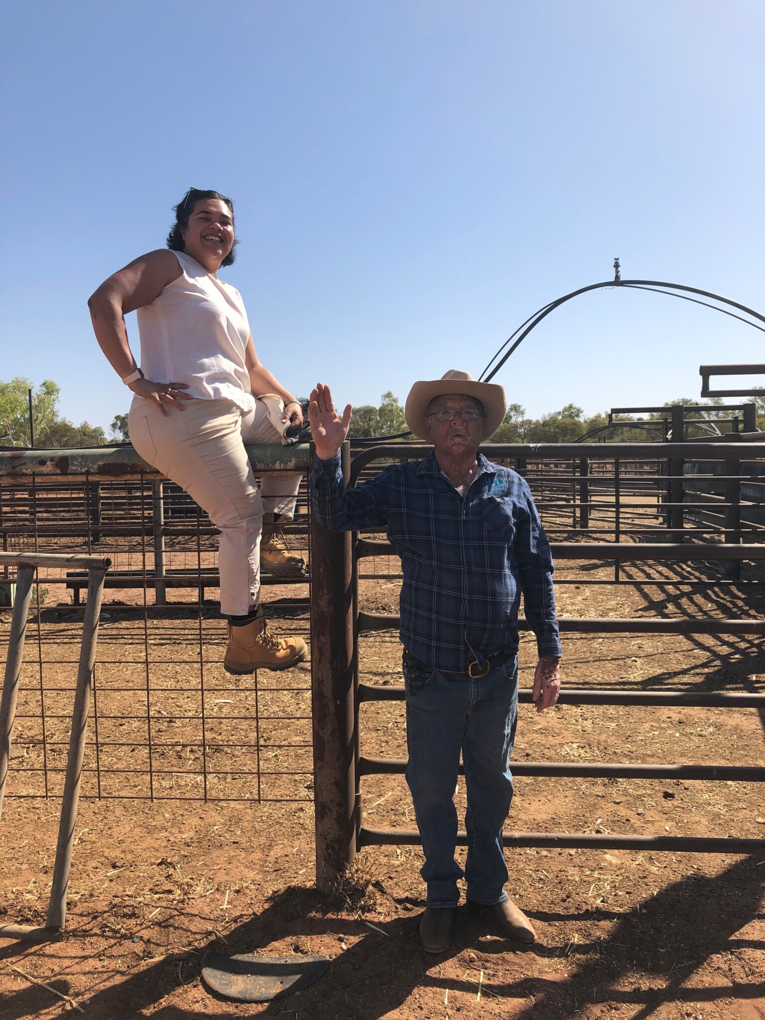 Rosie sits on wire fence as Peter stands and waves at camera