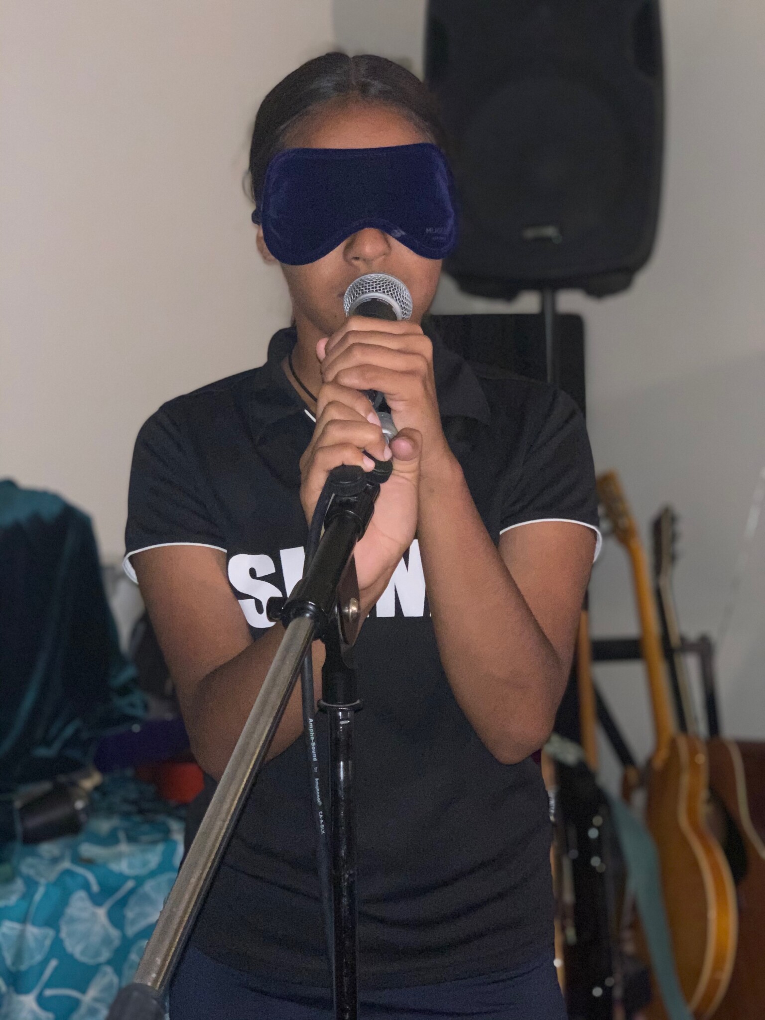 blindfolded singer holds a microphone.