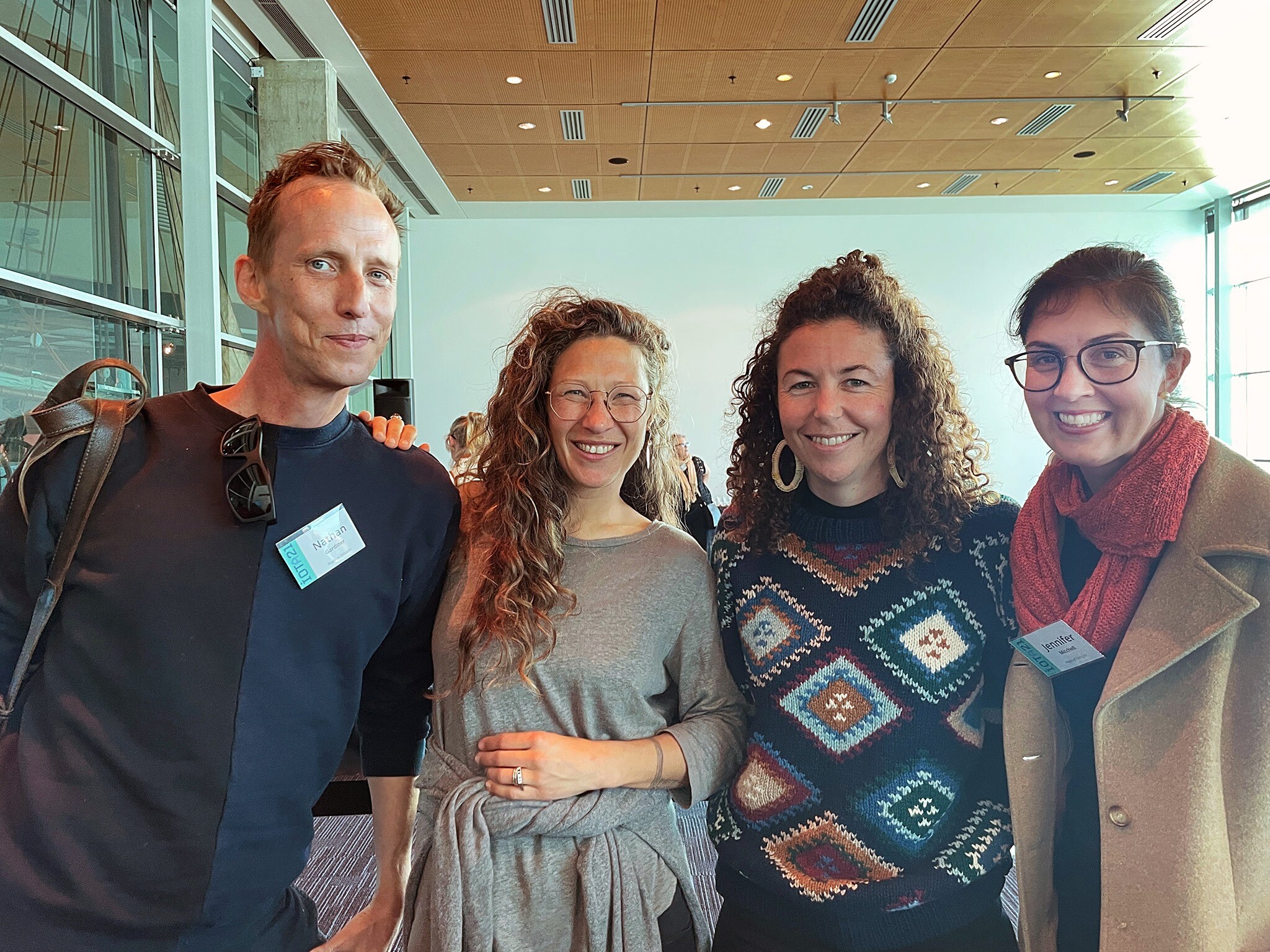 Four people in casual clothes stand indoors for a photo.