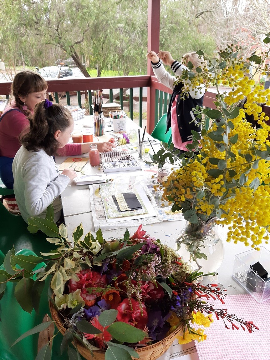 people learning how to press flowers, with a selection of flowers on the table.
