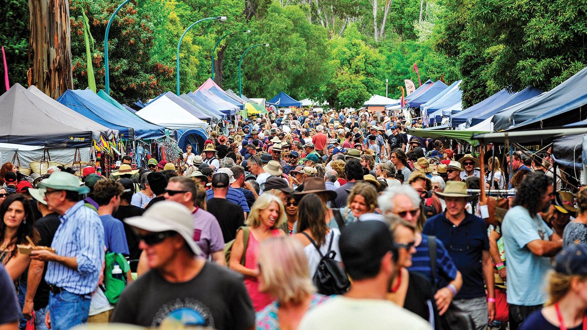 A crowd of people walking through a market stall