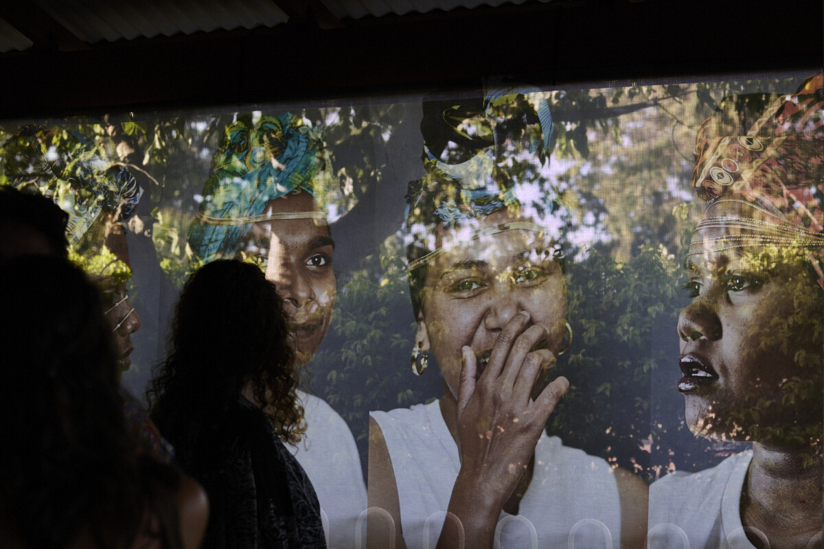 Group of people in front of a screen showing trees and foliage superimposed over portrait images.