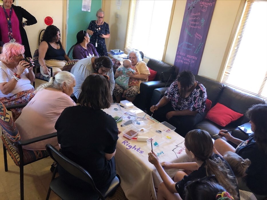 A group of people sitting around a desk covered in arts and crafts tools.