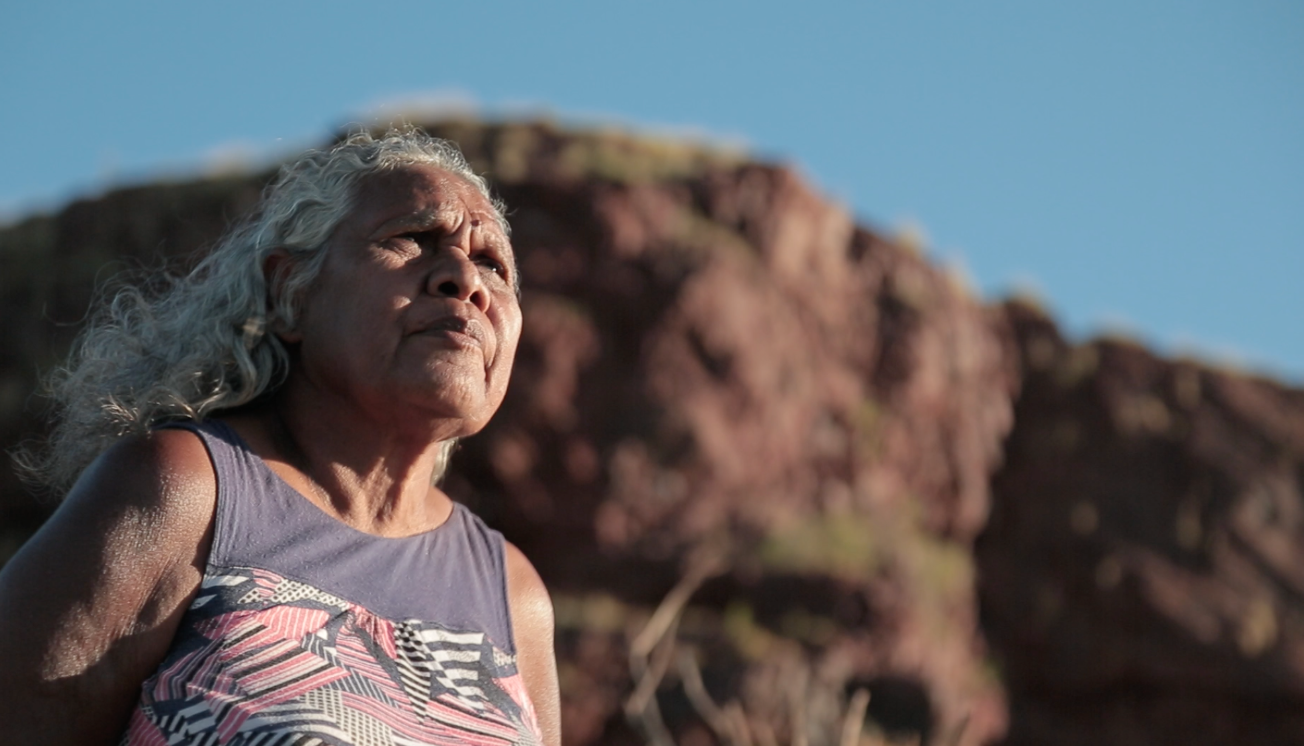 An Indigenous woman stares out to the sky.