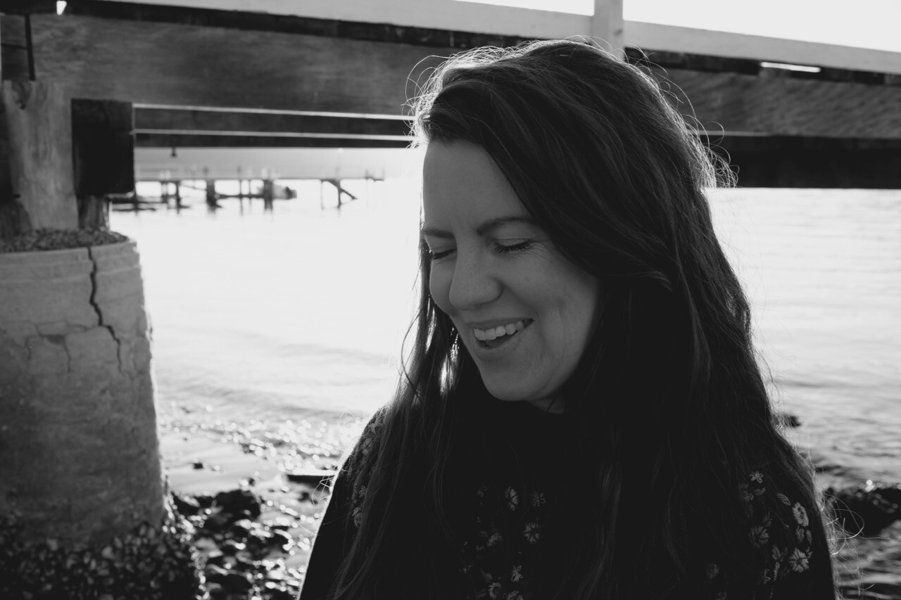 Black and white photo of Alana Hunt laughing with her eyes closed.