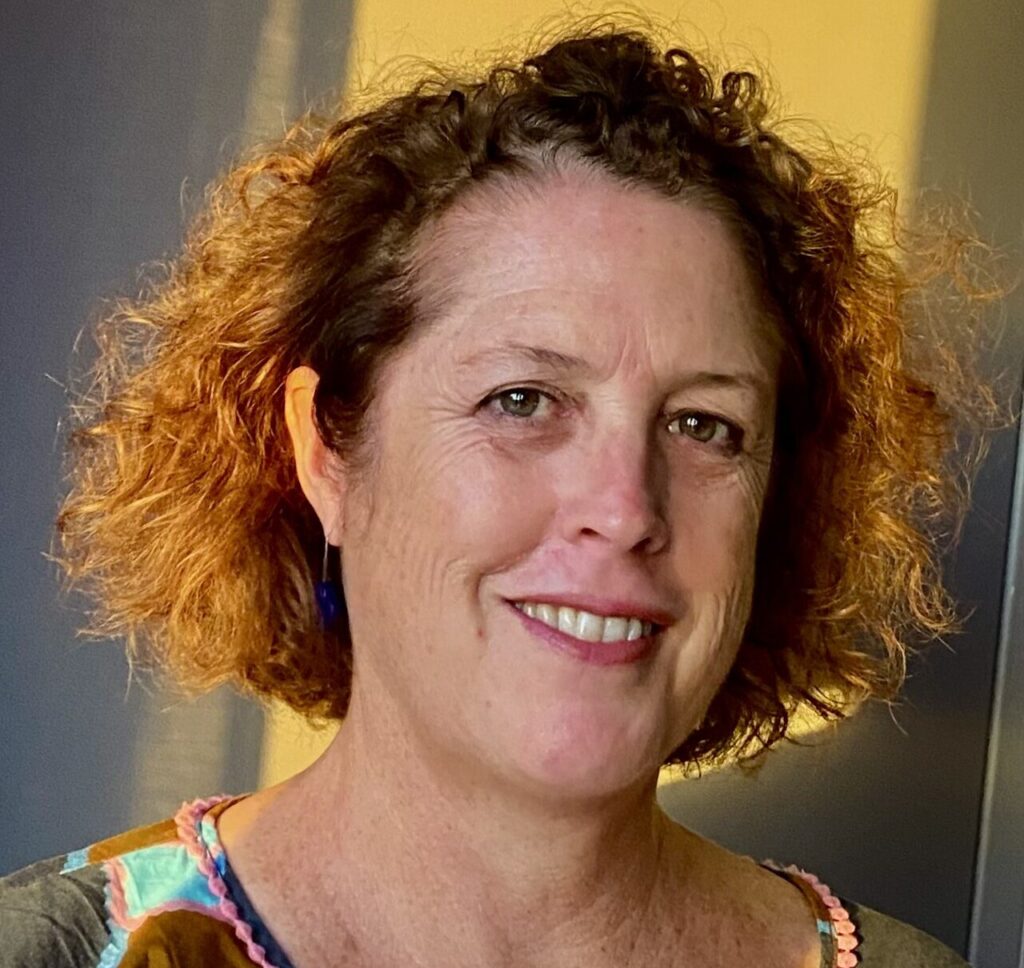 Woman with curly orange hair smiles at the camera