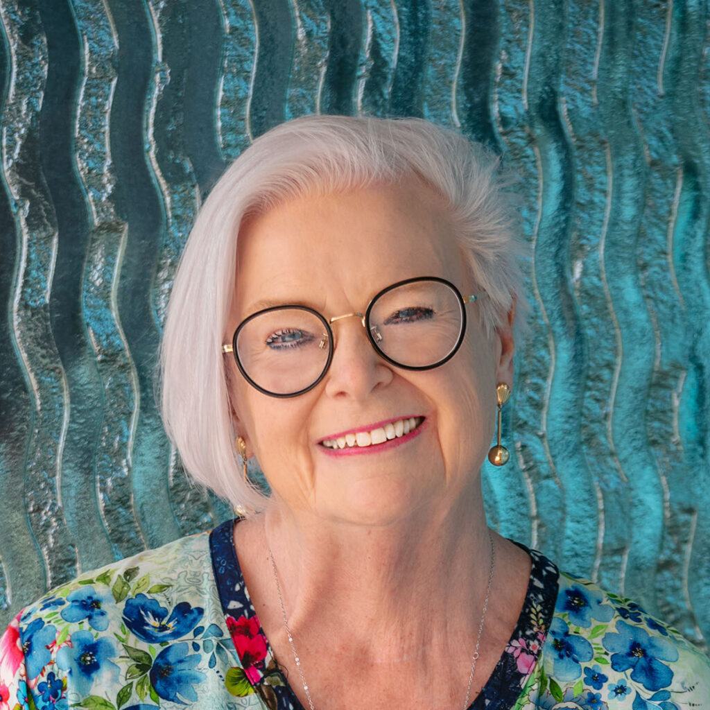 Headshot of Lesley Wilkinson wearing black frame reading glasses and a colour floral shirt