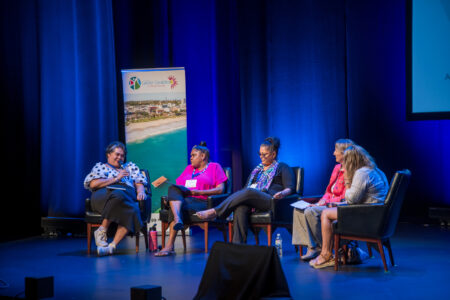 People sitting on a stage talking with a blue background