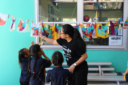 Jackie Cheng holds a piece of art while three small children look up at it