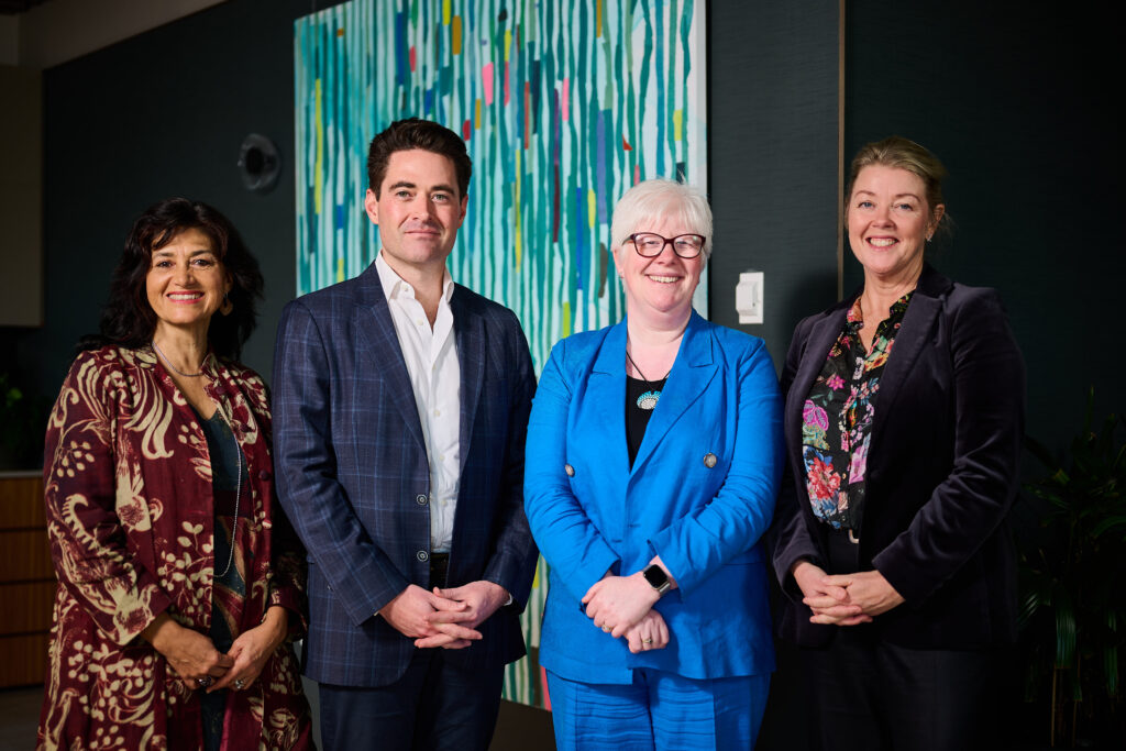 Four people in a corporate photo standing side by side