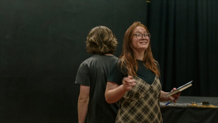 two young people one facing forward the other with back to camera