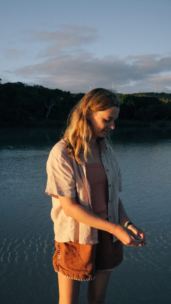 A woman standing in shallow waters at sunset.