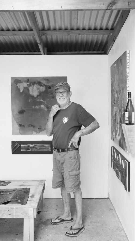 Black and white photo with man standing in front of paintings on a wall
