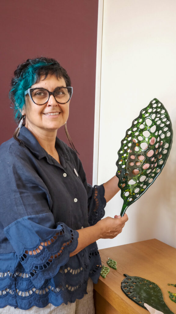 Woman holding green glass art.