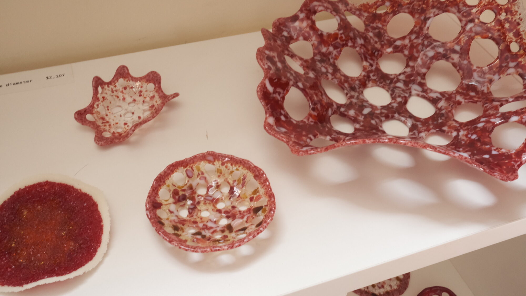 Red glass artwork on a white shelf.