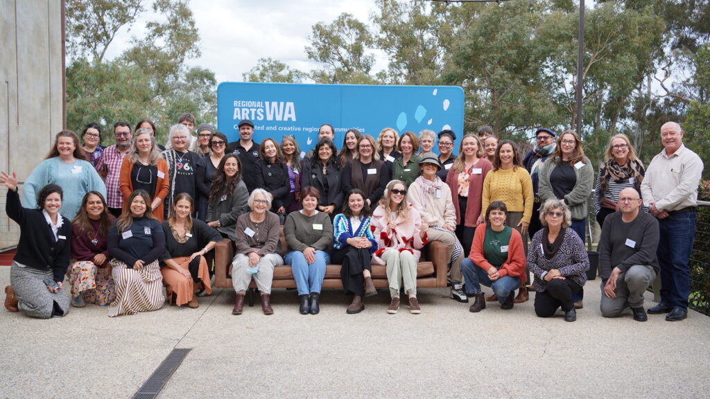 A group of people outside posing for a group photo in front of a branded backdrop.