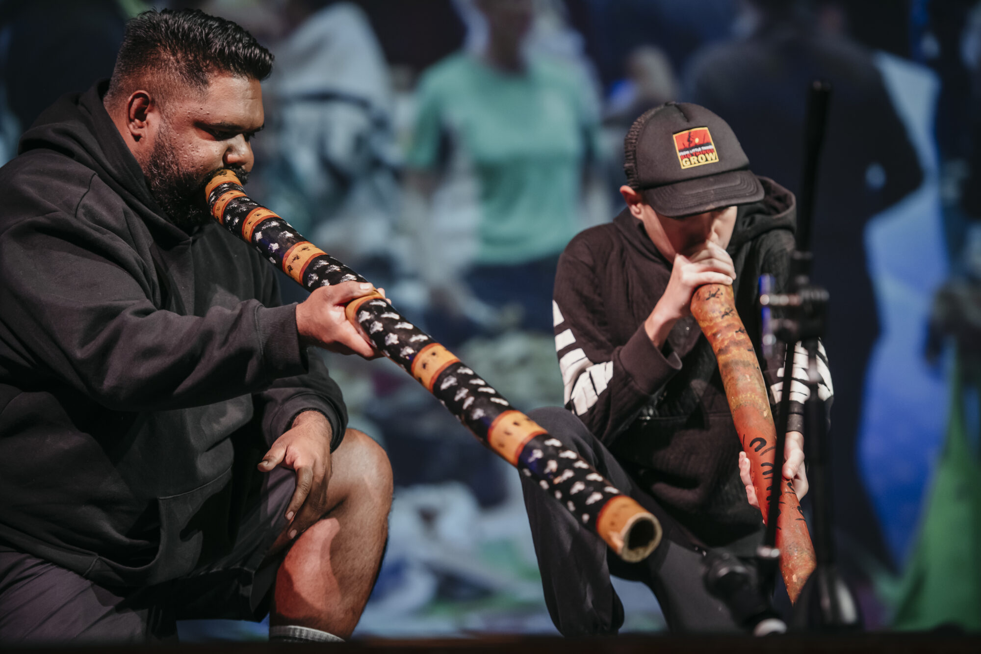 Two men on stage playing the didgeridoo.