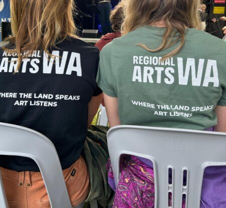 Two people with their back towards the camera. The RAWA logo is on the back of their shirts.
