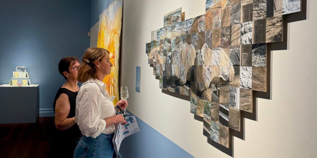 Two people looking at art installation of multiple canvas.