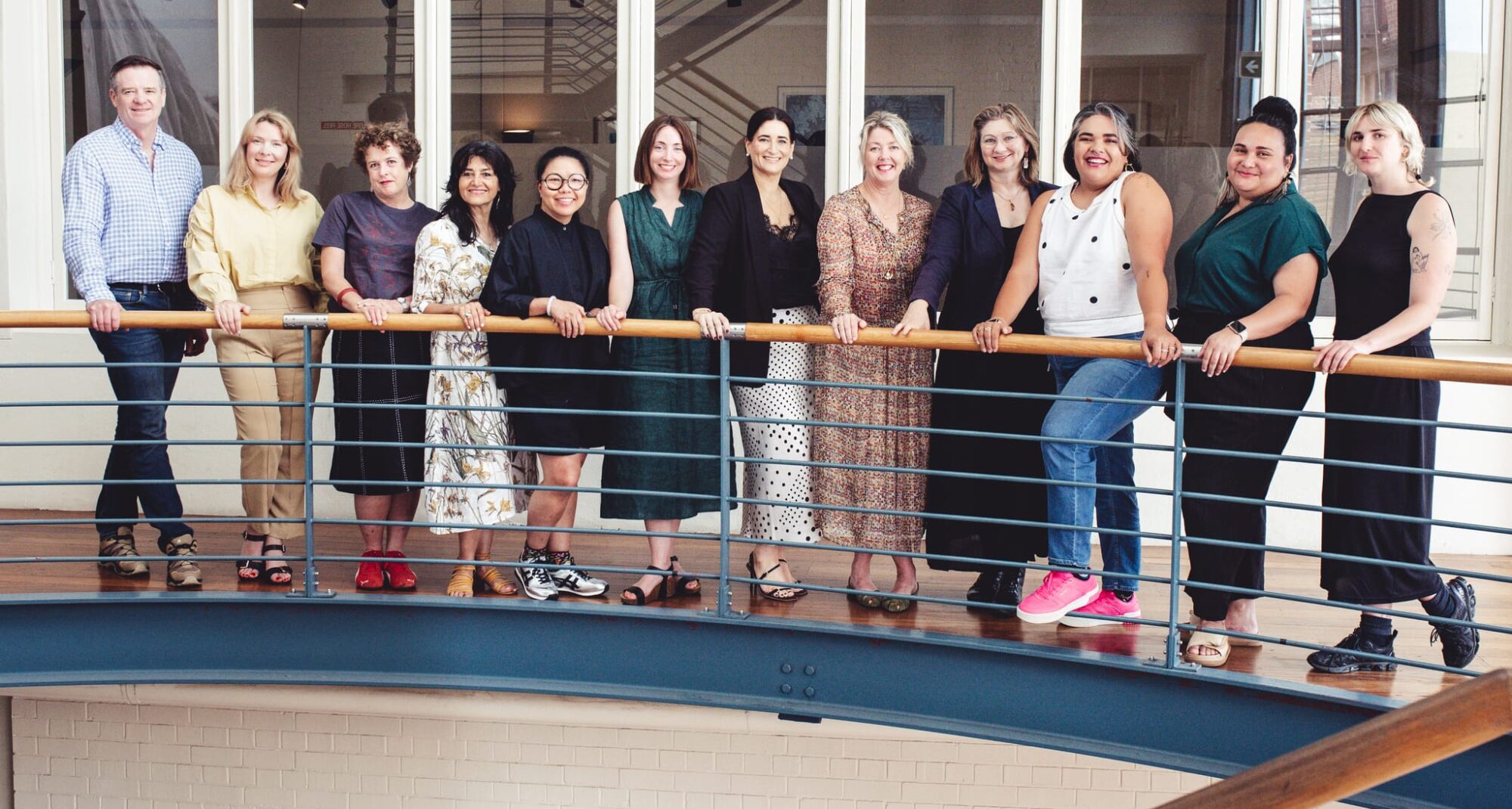 A group shot of a row of people posing on an interior balcony.